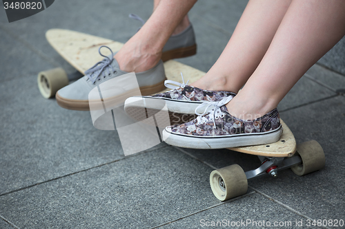 Image of Feet couple of teenagers in sneakers on longboard closeup