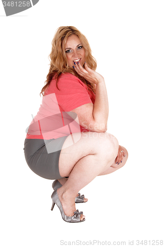 Image of Plus size woman crouching in shorts and heels.