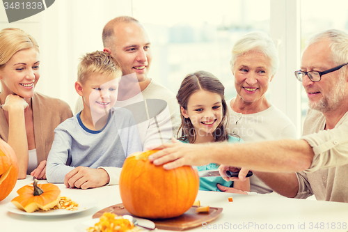 Image of happy family sitting with pumpkins at home