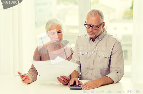 Image of senior couple with papers and calculator at home