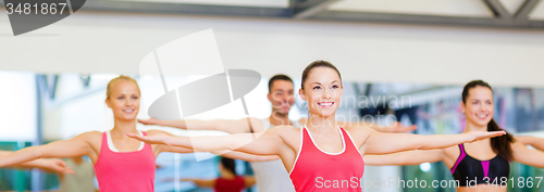 Image of group of smiling people exercising in the gym