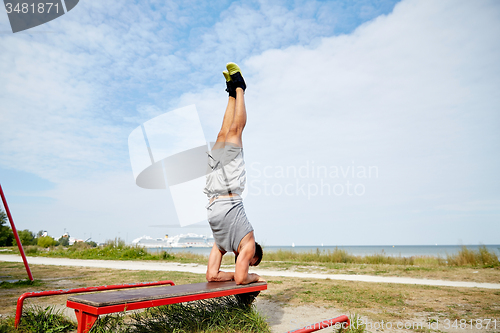 Image of young man exercising on bench outdoors