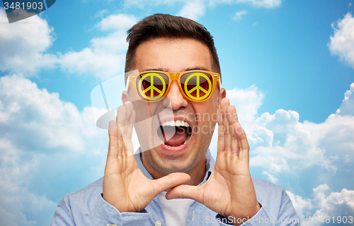 Image of face of shouting man in green peace sunglasses