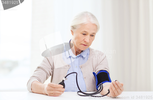 Image of old woman with tonometer checking blood pressure