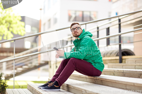 Image of young hipster man with smartphone in city