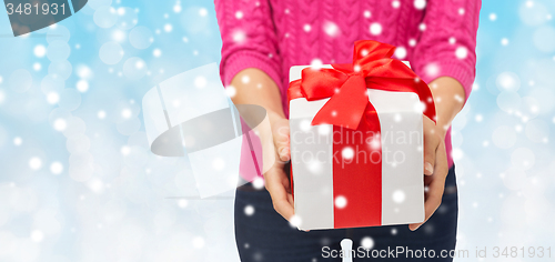 Image of close up of woman in pink sweater holding gift box