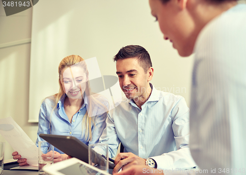 Image of smiling businesspeople with tablet pc in office