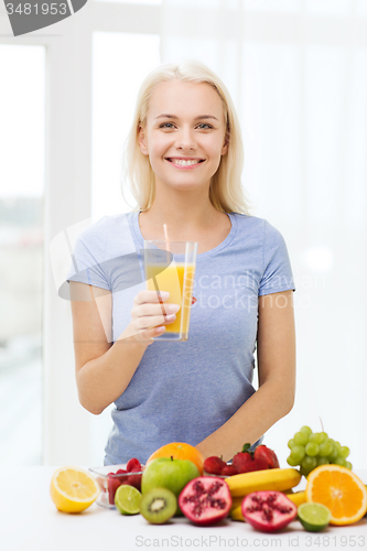 Image of smiling woman drinking fruit juice at home