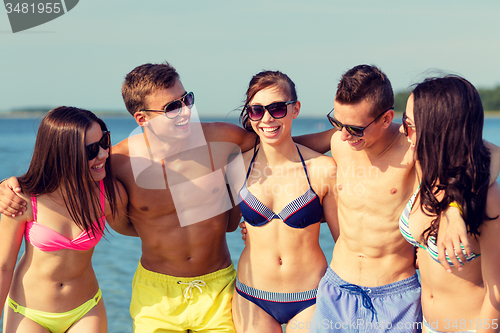 Image of smiling friends in sunglasses on summer beach