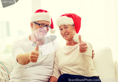 Image of happy senior couple in santa helper hats at home