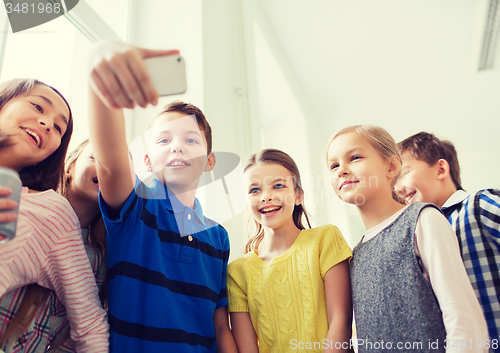 Image of group of school kids taking selfie with smartphone