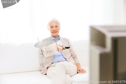 Image of happy senior woman watching tv at home