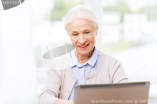 Image of happy senior woman with laptop at home