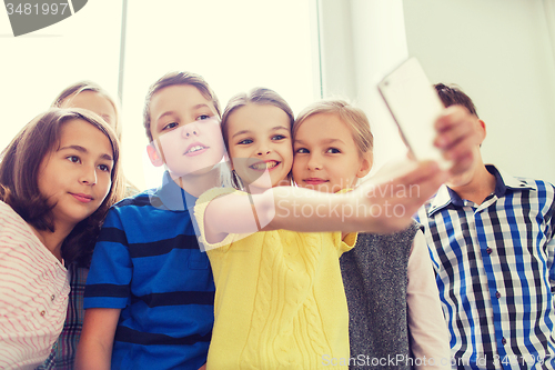 Image of group of school kids taking selfie with smartphone