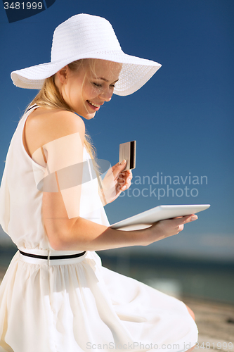 Image of woman in hat doing online shopping outdoors