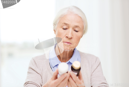 Image of senior woman with medicine jars at home