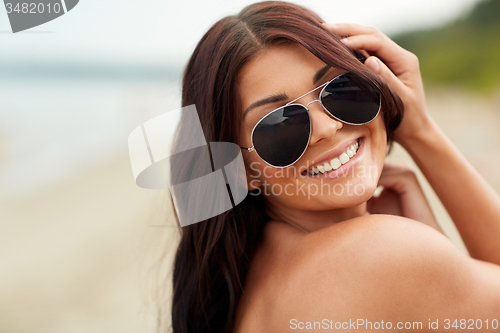 Image of smiling young woman with sunglasses on beach