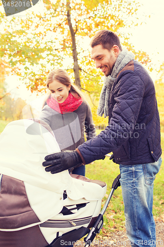 Image of smiling couple with baby pram in autumn park