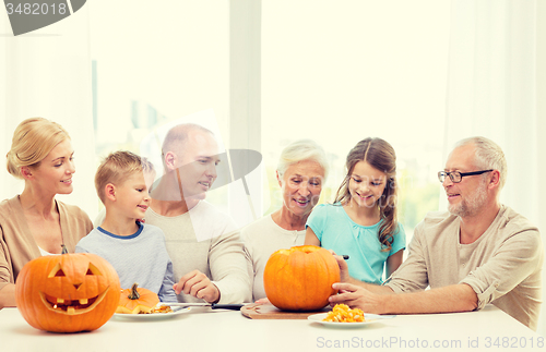 Image of happy family sitting with pumpkins at home