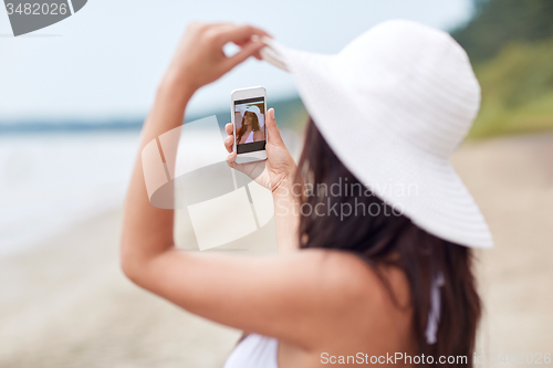 Image of young woman taking selfie with smartphone