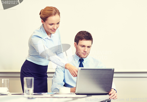 Image of businessman and secretary with laptop in office