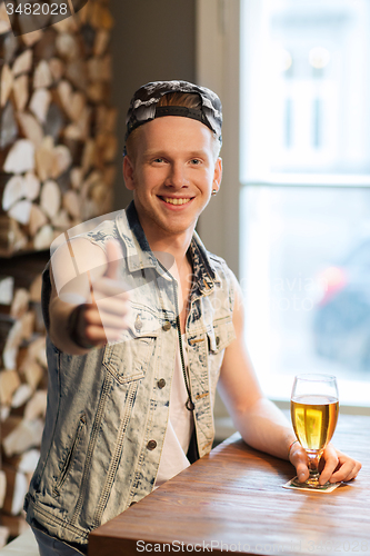 Image of happy man with beer showing thumbs up at bar