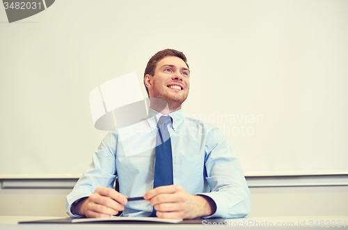 Image of smiling businessman sitting in office