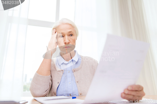 Image of senior woman with papers and calculator at home