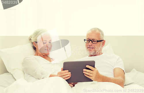 Image of happy senior couple with tablet pc at home