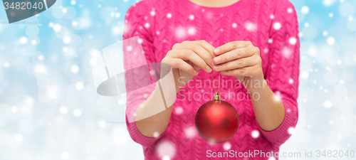 Image of close up of woman in sweater with christmas ball