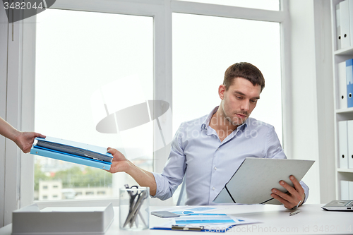 Image of businessman taking papers from secretary in office