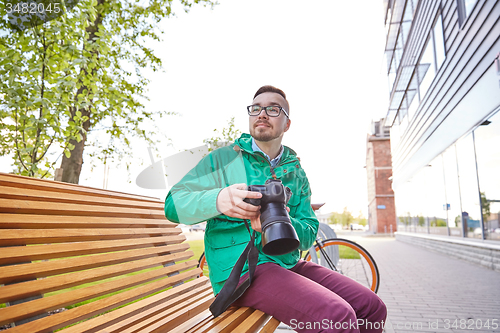 Image of young hipster man with digital camera in city