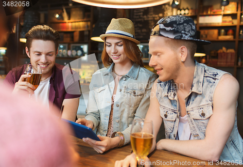 Image of happy friends with tablet pc and drinks at bar