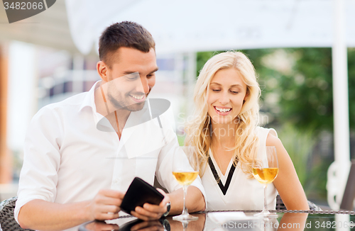 Image of happy couple with wallet and bill at restaurant