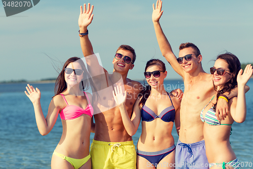 Image of smiling friends in sunglasses on summer beach