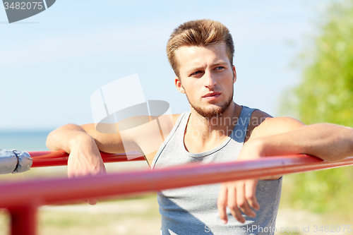 Image of young man exercising on parallel bars outdoors