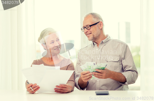 Image of senior couple with money and calculator at home