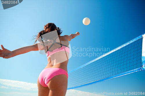 Image of young woman with ball playing volleyball on beach