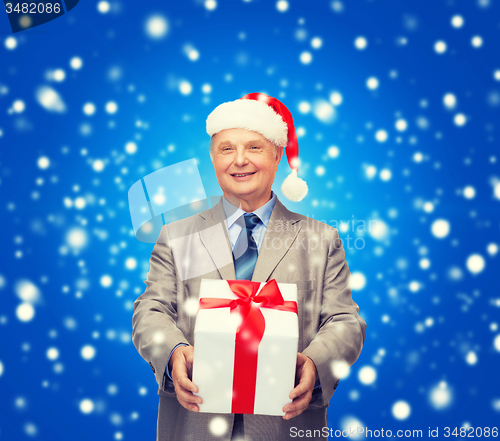 Image of smiling man in suit and santa helper hat with gift