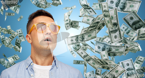 Image of surprised man under dollar money rain