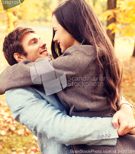 Image of smiling couple hugging in autumn park