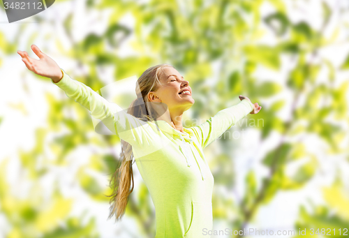 Image of happy woman in sport clothes raising hands
