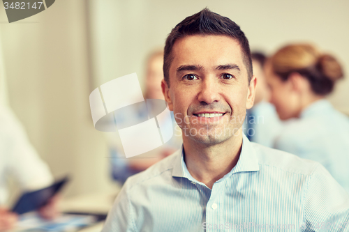 Image of group of smiling businesspeople meeting in office