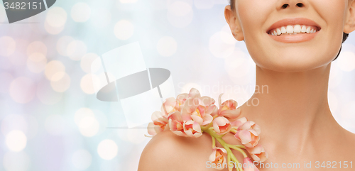 Image of close up of smiling woman with orchid flower