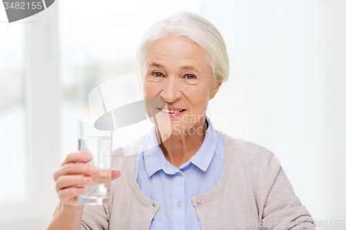 Image of happy senior woman with glass of water at home