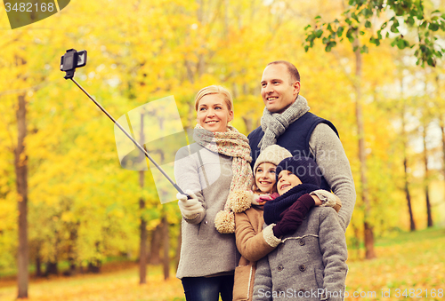 Image of happy family with smartphone and monopod in park