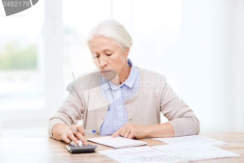 Image of senior woman with papers and calculator at home