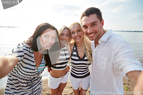Image of happy friends on beach and taking selfie