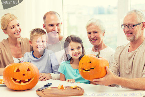 Image of happy family sitting with pumpkins at home