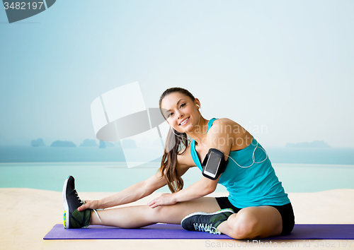 Image of smiling woman stretching leg on mat over pool